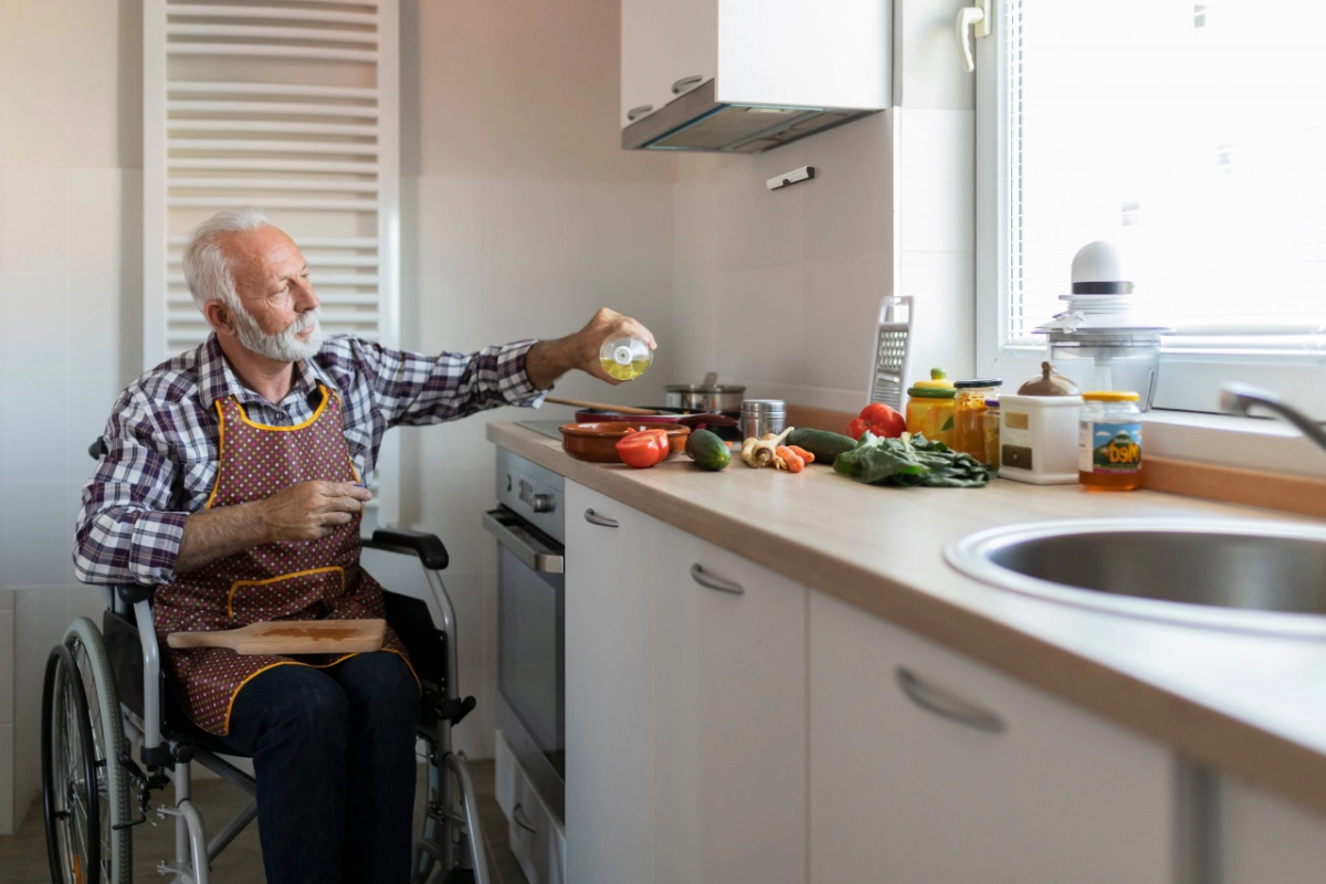Ein Mann im Rollstuhl kocht sicher mit installiertem Airis Herdschutz